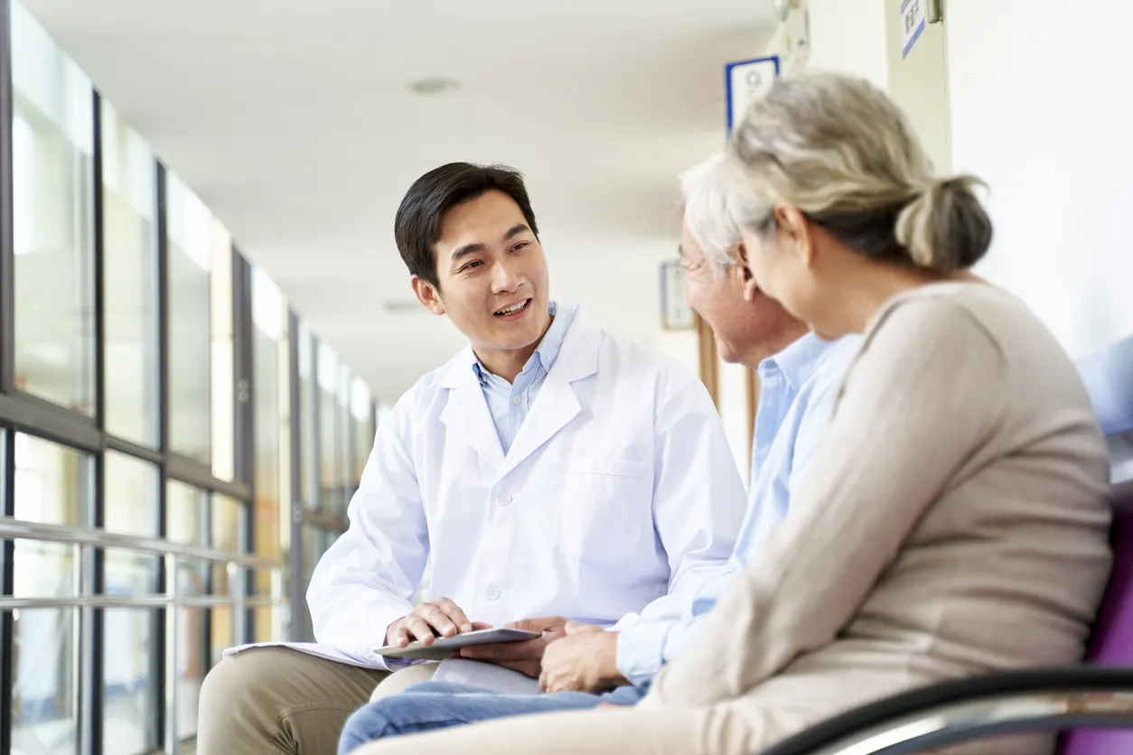 Two older patients with a doctor seated in a hallway