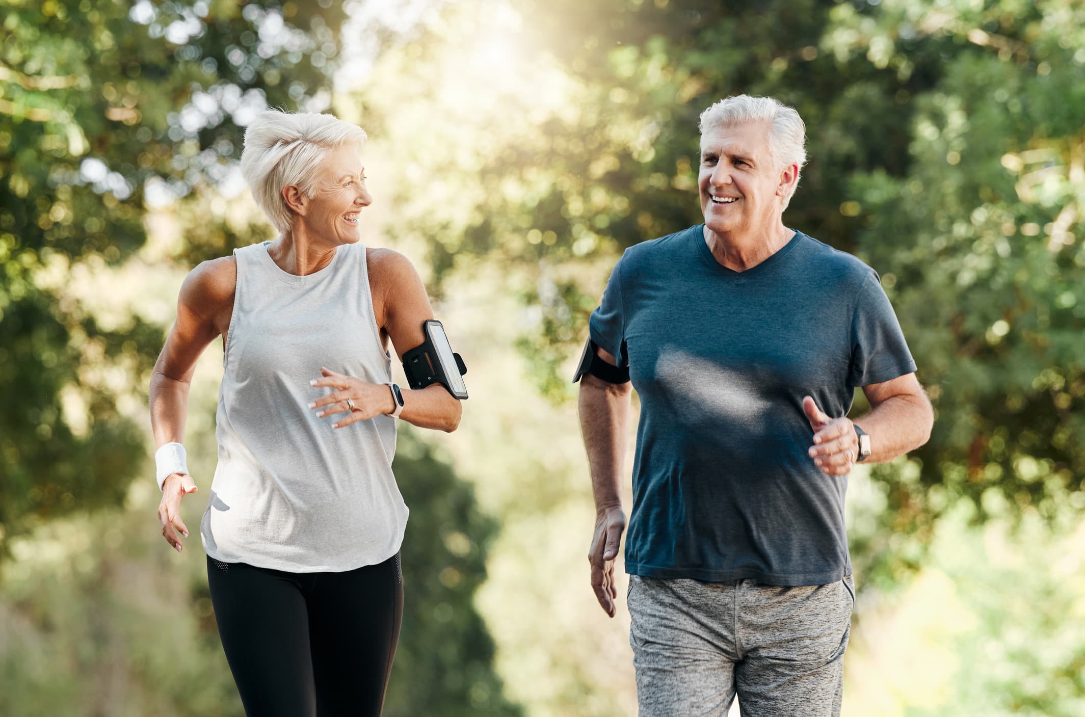 Health, senior couple and running in nature or park for exercise, fitness and wellness. Retirement, elderly man and woman enjoy walk, fresh air and talk in forest for workout, training and relax