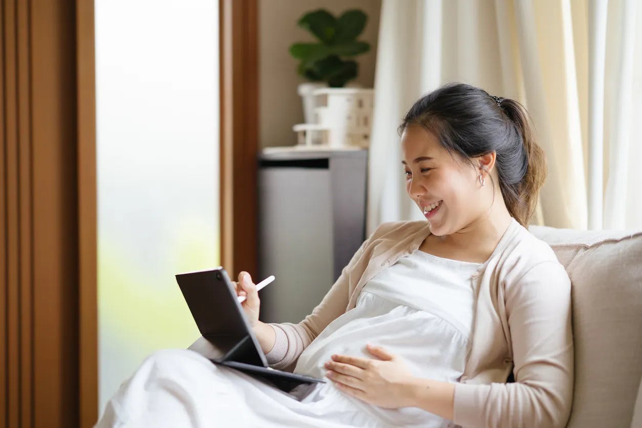 Pregnant woman using a tablet computer on a sofa