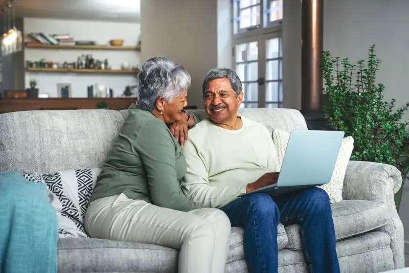 Older couple using a laptop on a sofa