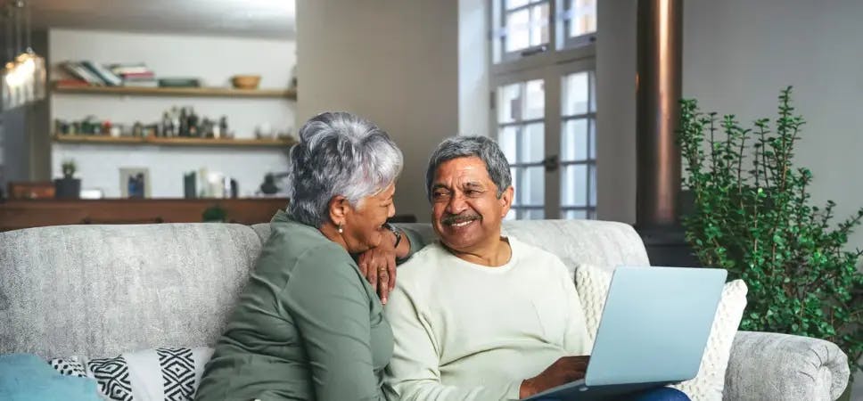 Older couple using a laptop on a sofa