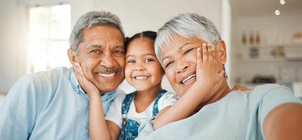 Happy granddaughter smiling between two grandparents 
