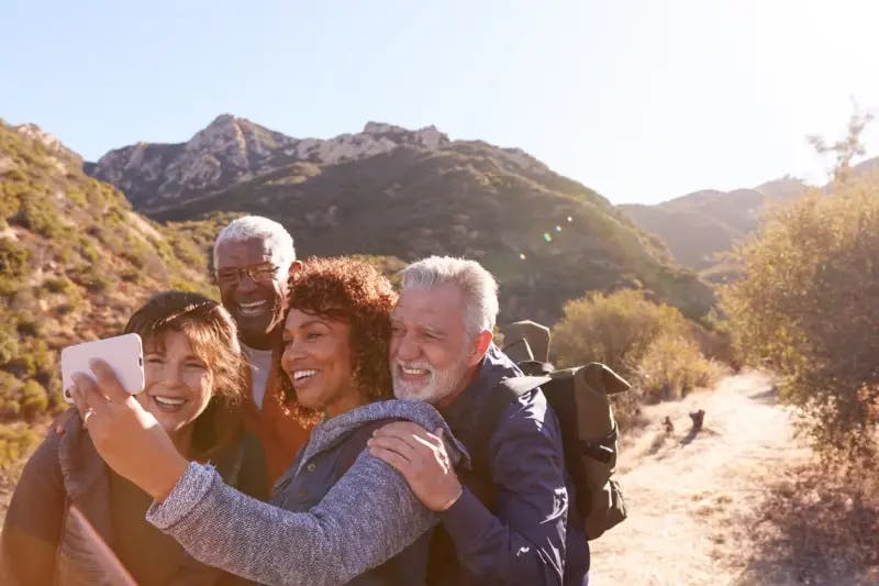 Two couples taking a selfie on a hiking trail