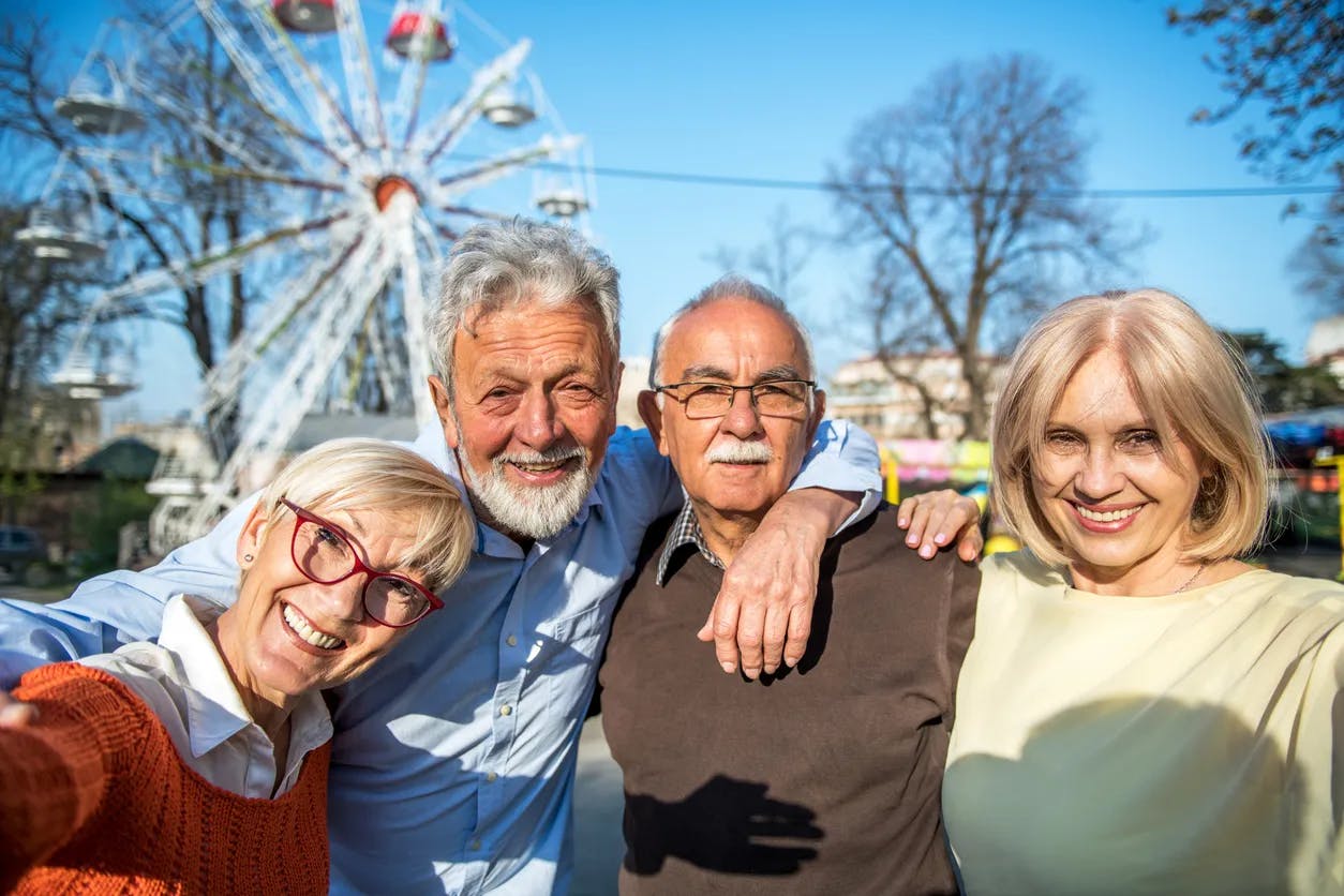 Two couples smiling with a ferris wheel in the background