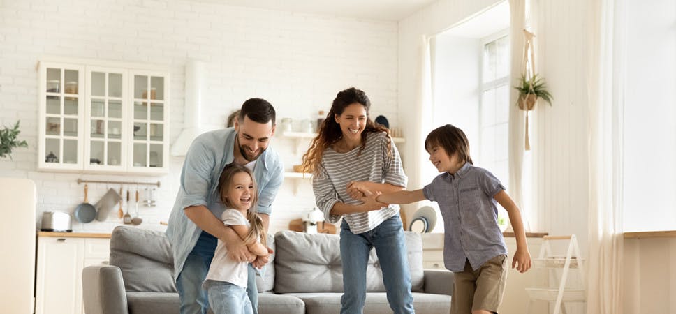 Family of four dancing in their living room