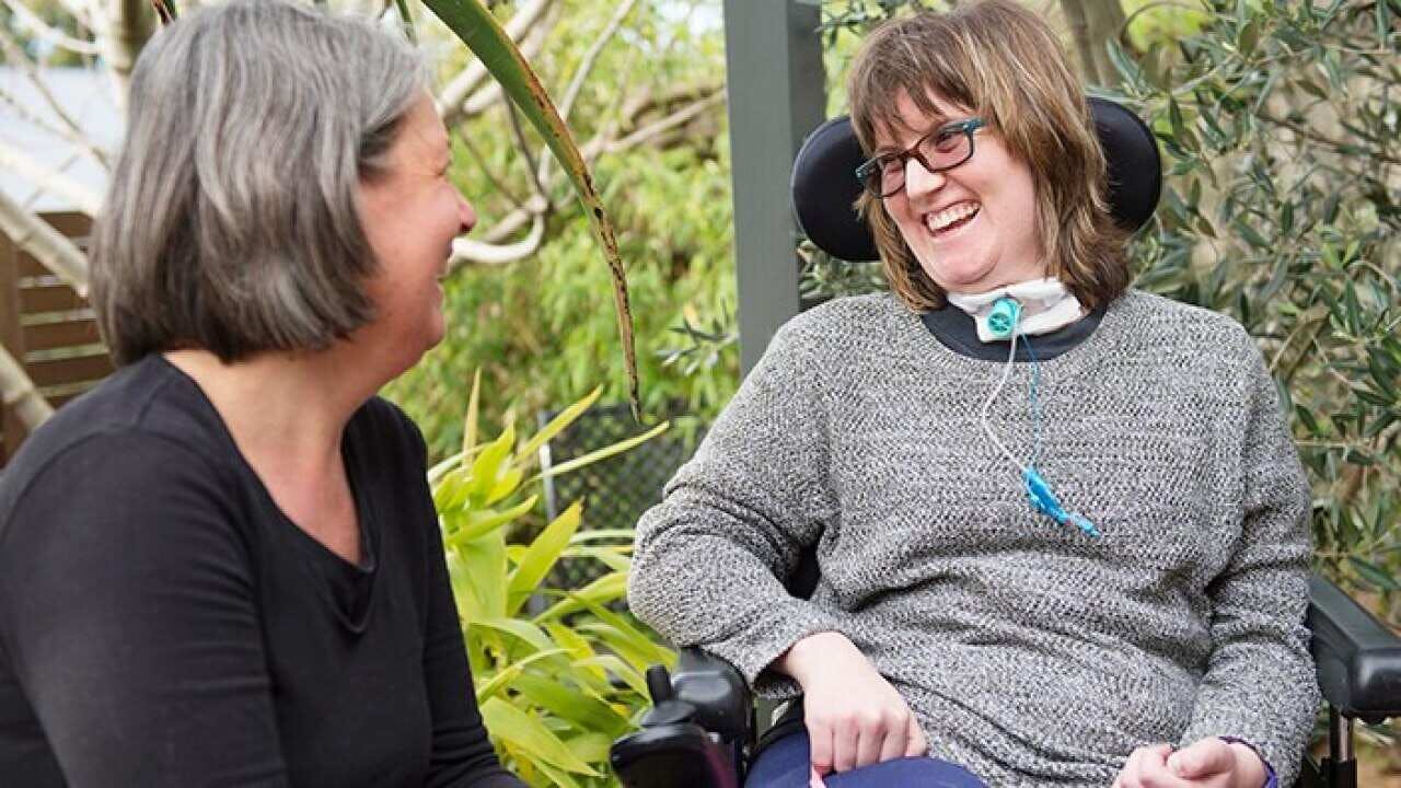 Disabled woman sitting in a wheelchair talking to another woman