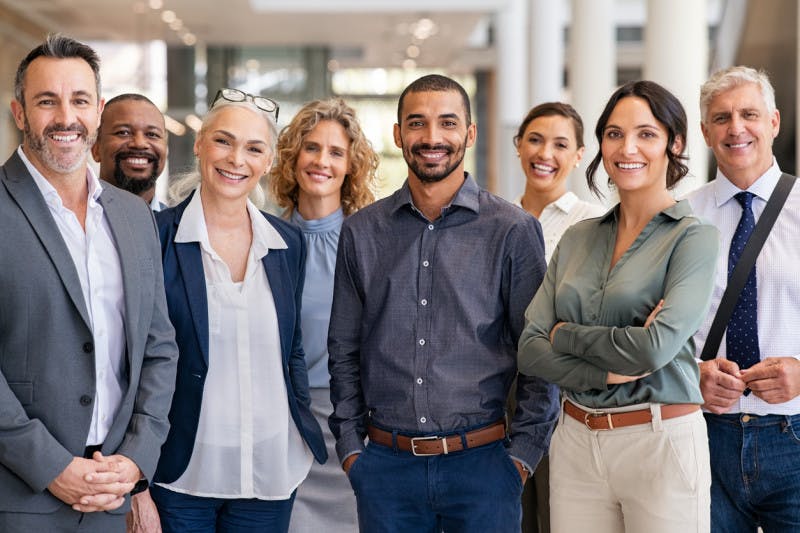 Portrait of successful group of business people at modern office looking at camera. Portrait of happy multiethnic businessmen and satisfied businesswomen standing as a team.