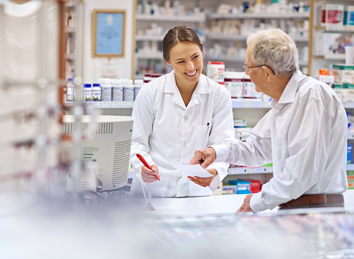 Shot of a young pharmacist helping an elderly customer at the prescription counter.