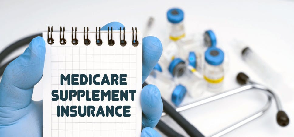 Hand-holding notebook written Medicare Supplement Insurance
