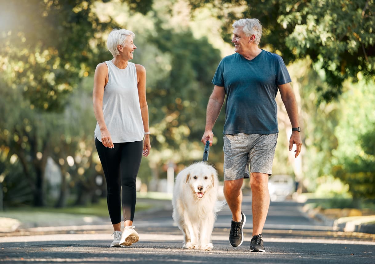 Two active seniors walk their dog
