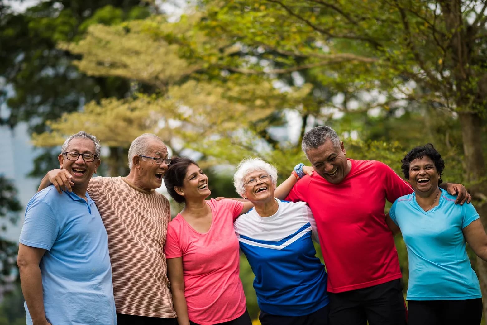Six people smiling and hugging outside