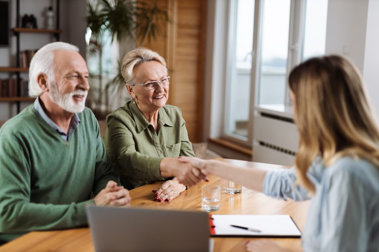 Senior man and woman shake hands with insurance agent after finding a policy that fits their Medicare needs and budget