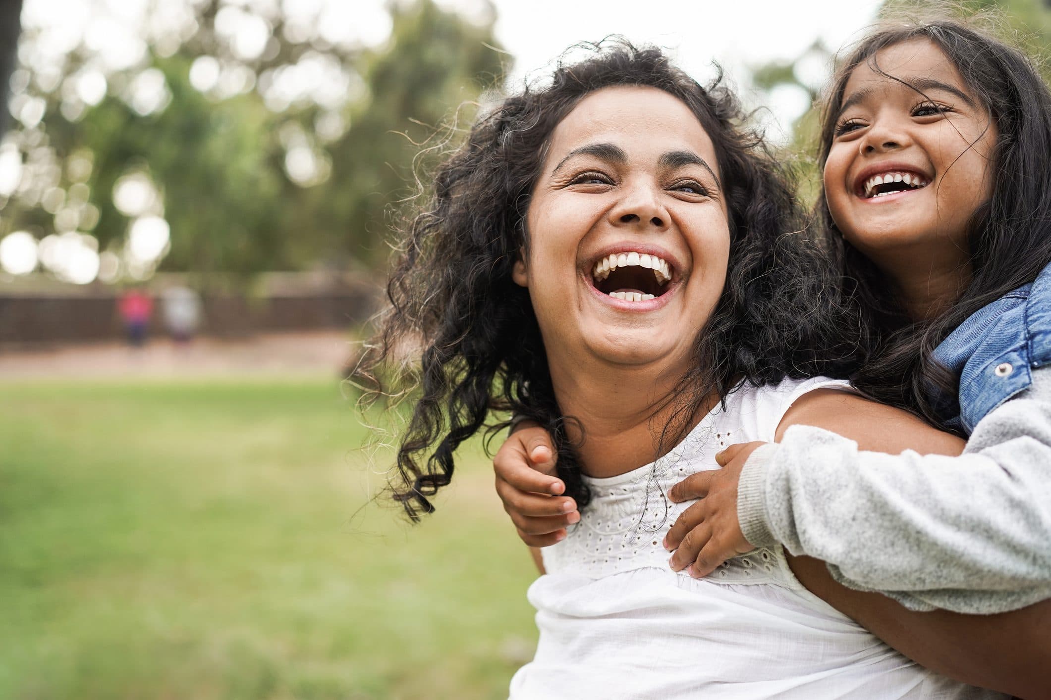Mother and daughter laughing together outdoors