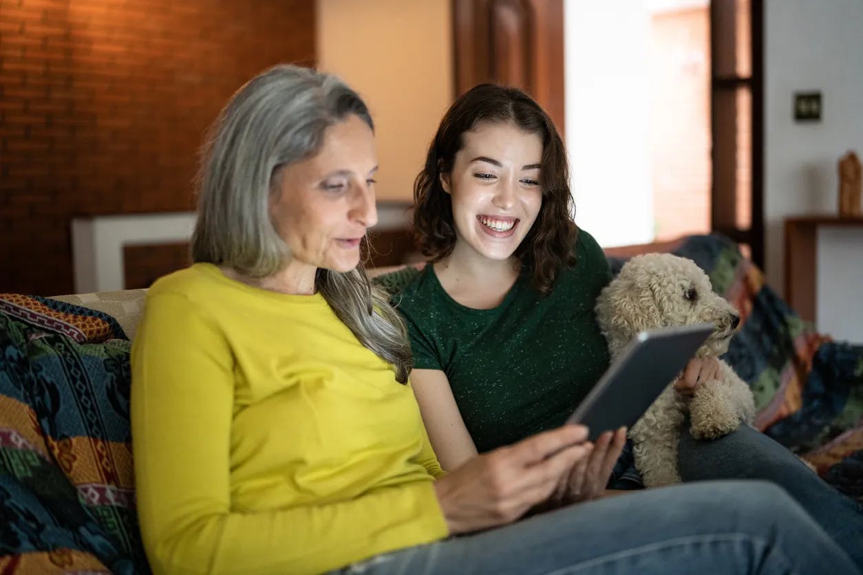Older woman and younger woman looking at a tablet computer on a sofa