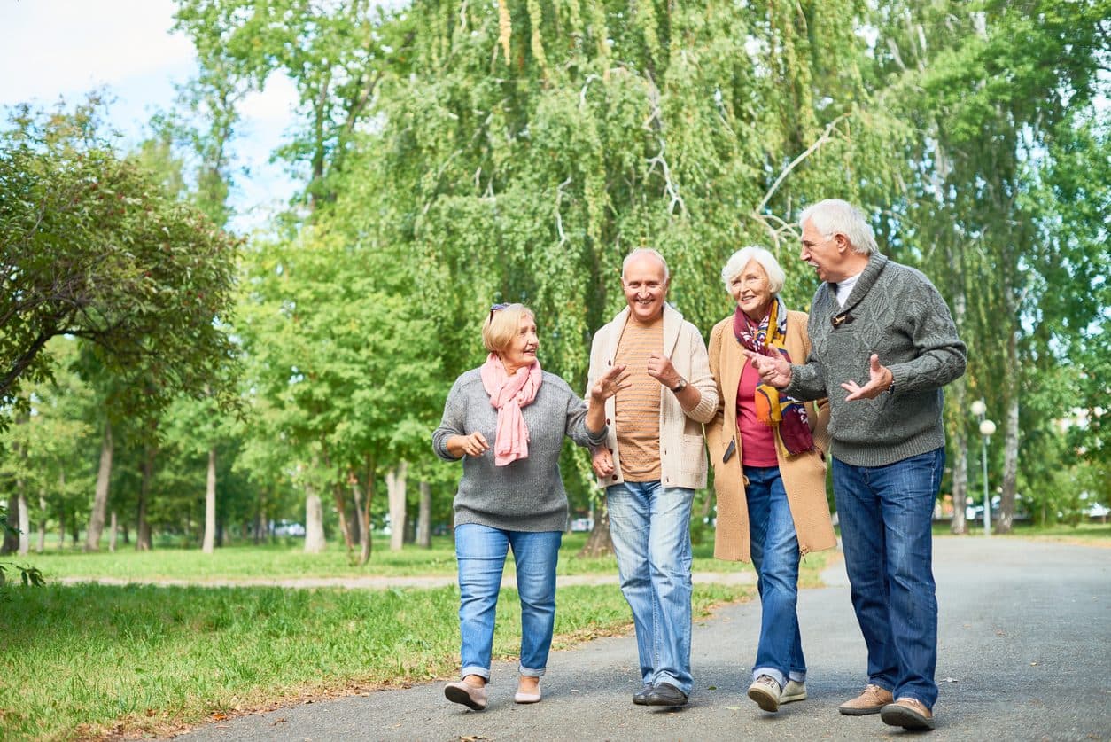 Group of older friends walking together through a park