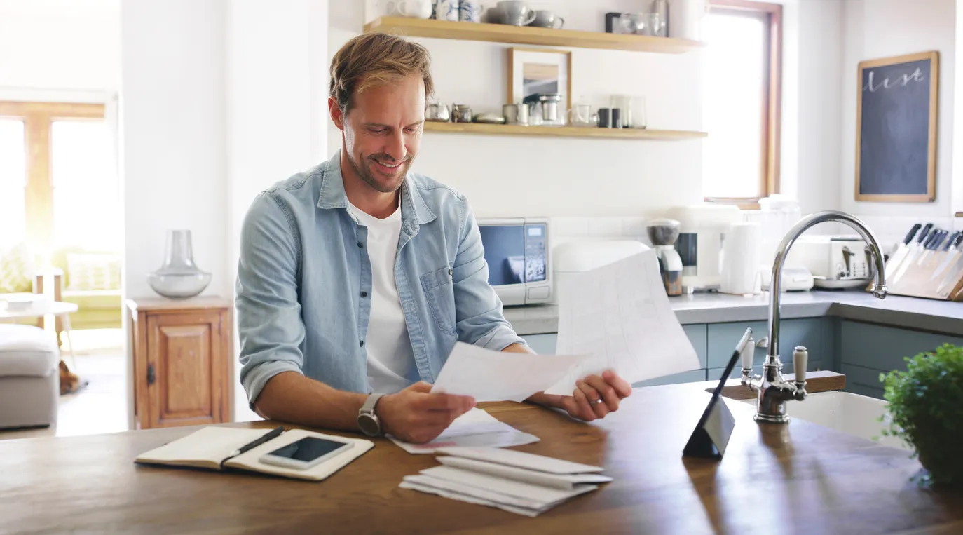 Man reading bills at kitchen counter