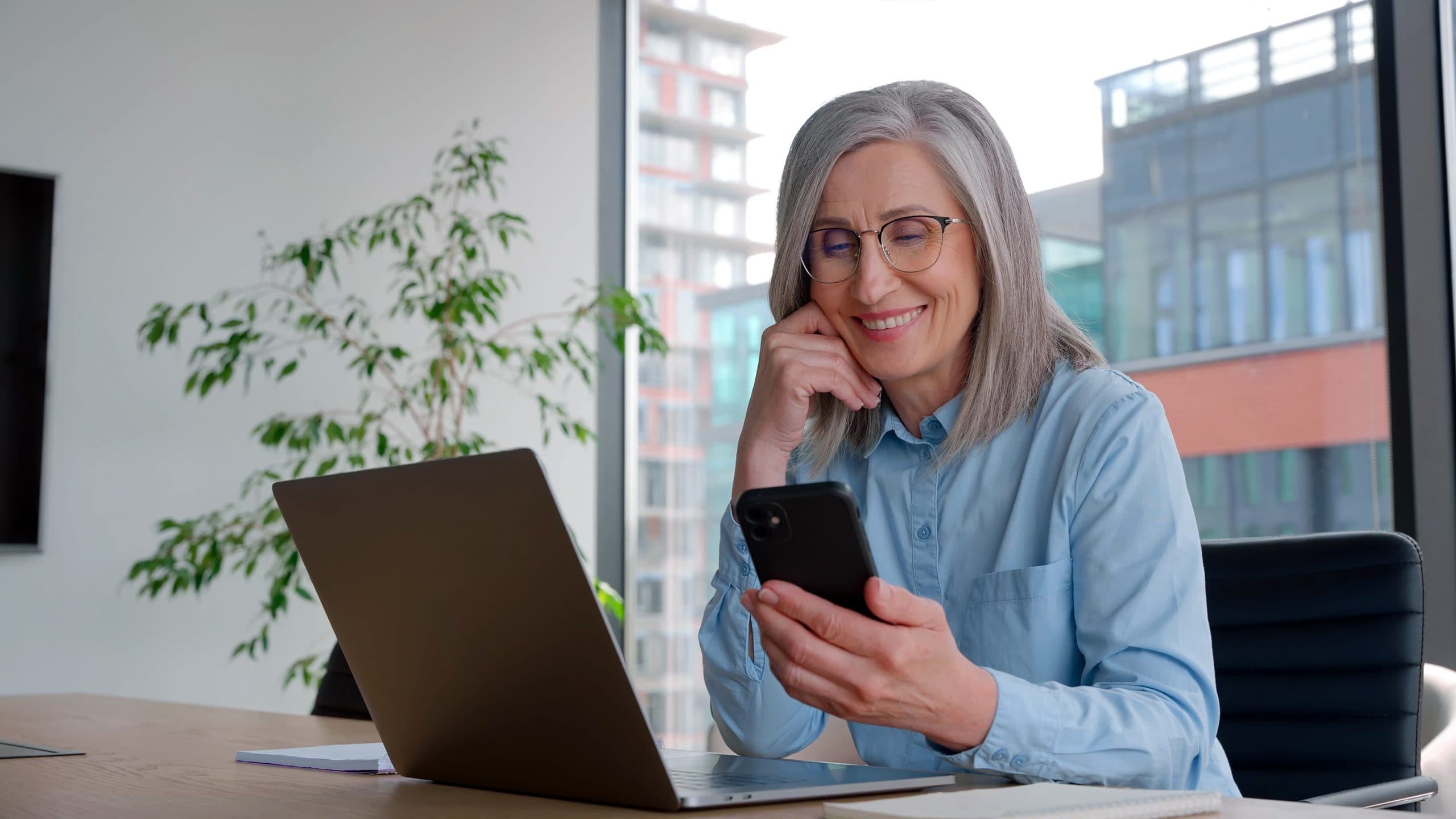 Older woman using a smartphone at her desk